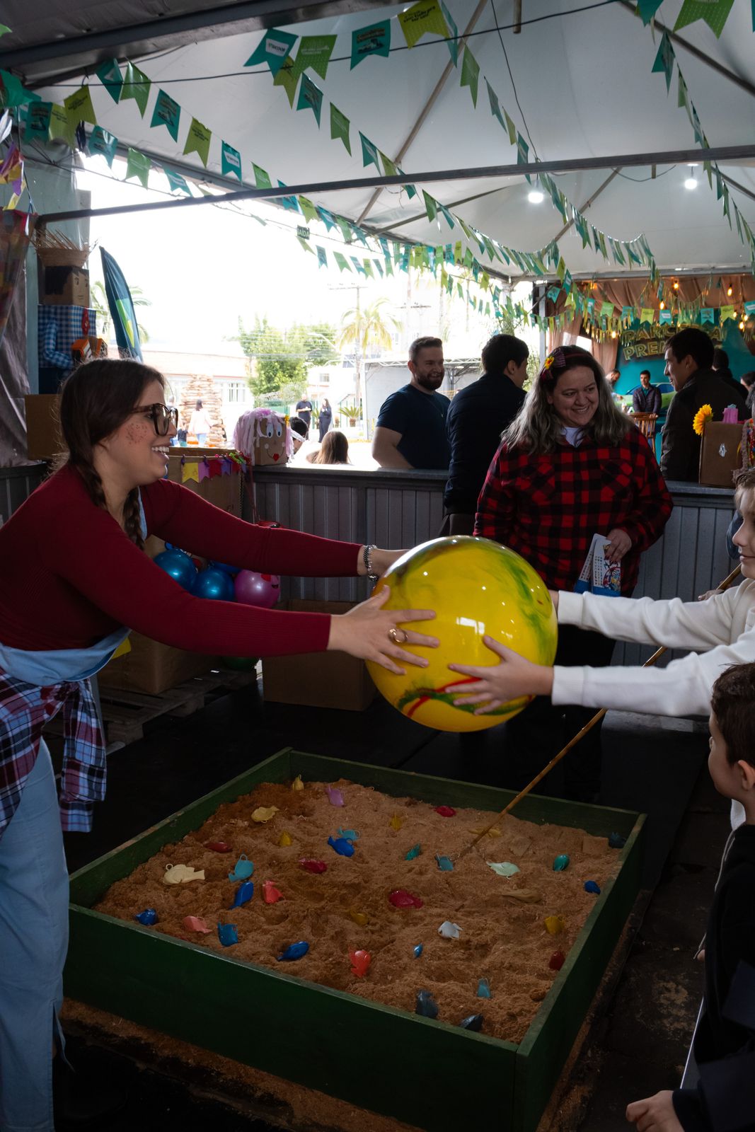Criança brincando na pescaria da festa, recebendo uma bola colorida
